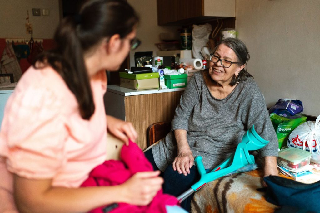 Pflegekraft unterstützt eine Seniorin mit Gehstütze