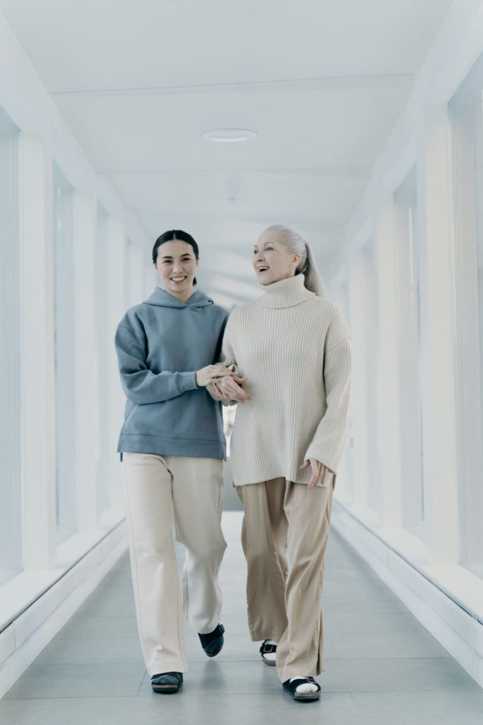 Seniorin und Begleiterin gehen Hand in Hand