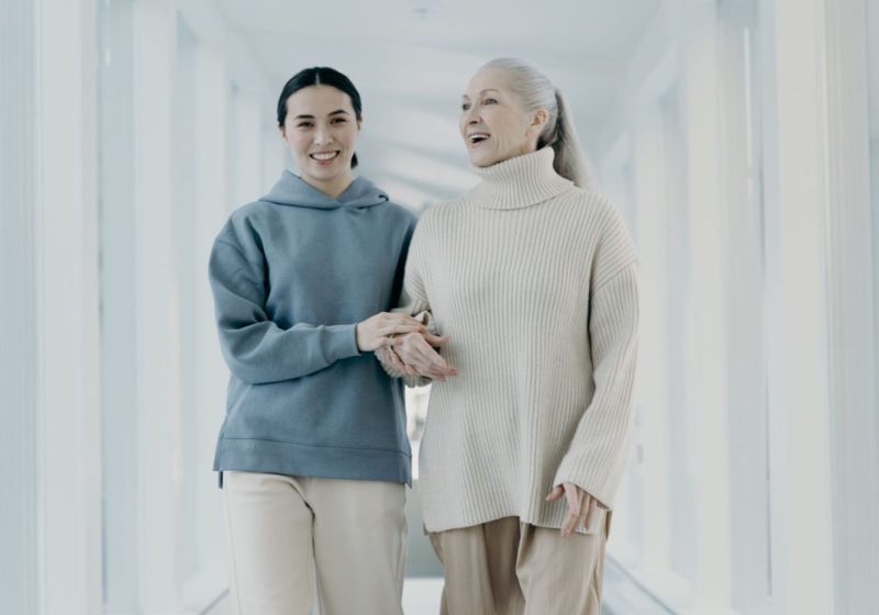 Seniorin und Begleiterin gehen Hand in Hand